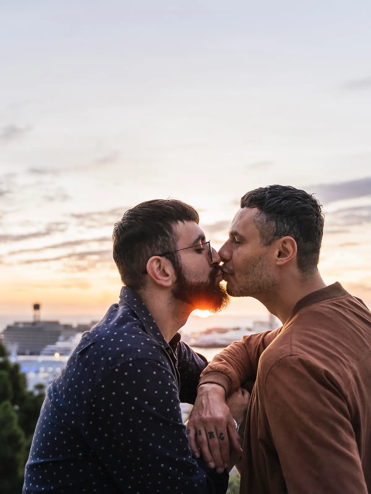 Gay couple kissing on lookout above the city with view to the port, Barcelona, Spain || Modellfreigabe vorhanden