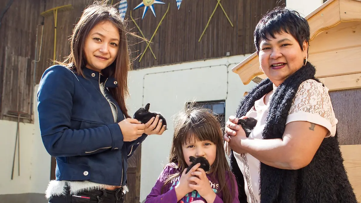 Jorafina (5) zeigt ihrer Mama Narumol (r.) und ihrer großen Halbschwester Jenny (18) stolz den neuen Familienzuwachs: Kleine, putzige Kaninchen bevölkern jetzt zusätzlich den Hof. Josef hat extra eigene neue Ställe für die flauschigen Vierbeiner gebaut.
