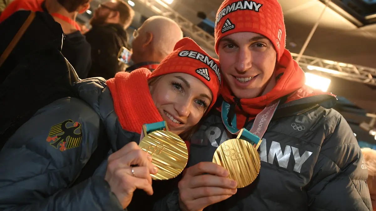 26.02.2018, Hessen, Frankfurt am Main: das Eiskunstlaufpaar Aljona Savchenko (r-l) und Bruno Massot wird nach der Landung der Lufthansa-Maschine LH713 mit mehr als 150 Sportlern, Trainern und Funktionären an Bord von Fans begrüßt und zeigt seine Goldmedaillen. Foto: Arne Dedert/dpa +++ dpa-Bildfunk +++