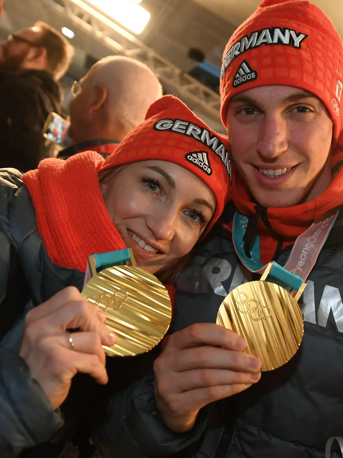 26.02.2018, Hessen, Frankfurt am Main: das Eiskunstlaufpaar Aljona Savchenko (r-l) und Bruno Massot wird nach der Landung der Lufthansa-Maschine LH713 mit mehr als 150 Sportlern, Trainern und Funktionären an Bord von Fans begrüßt und zeigt seine Goldmedaillen. Foto: Arne Dedert/dpa +++ dpa-Bildfunk +++