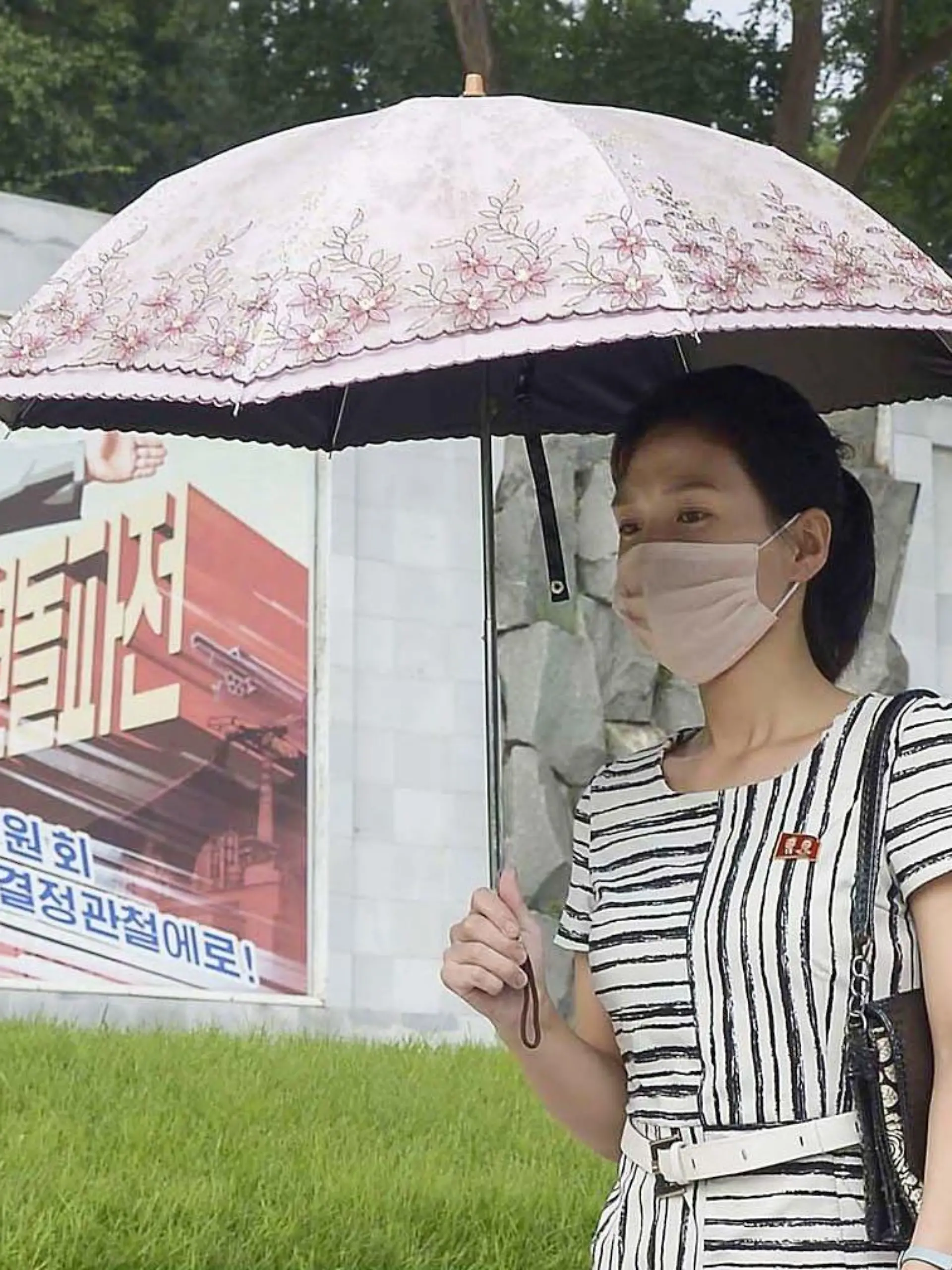 Frau mit Schirm und Maske in Nordkorea.