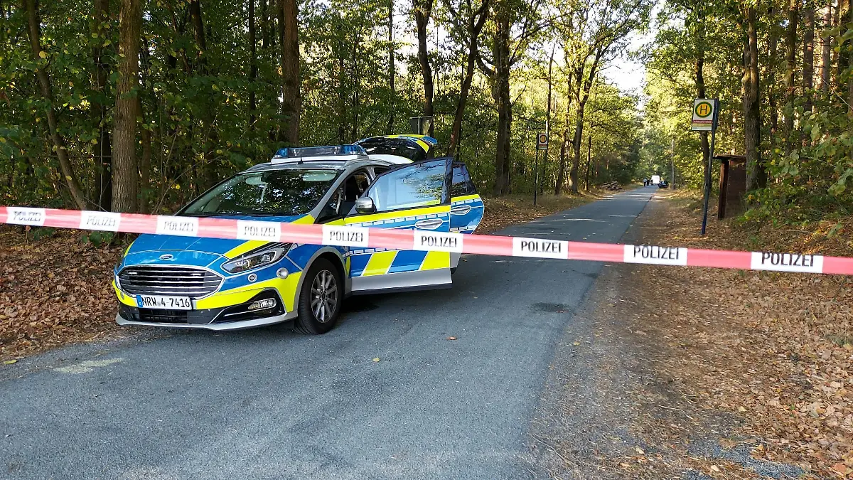 ARCHIV - 30.08.2022, Nordrhein-Westfalen, Saerbeck: Ein Polizeiauto steht an einem mit Flatterband abgesperrten Waldweg. Im Fall einer getöteten 25-Jährigen muss sich von Montag (27.02.) an ein Mann aus Greven vor Gericht verantworten. Er soll seine Nachbarin erwürgt und die Leiche anschließend in einem Waldstück versteckt haben. Foto: David Poggemann/Nord-West-Media/dpa +++ dpa-Bildfunk +++