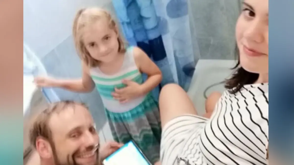 Frau stellt Füße in die Dusche, Mann und Tochter stehen daneben