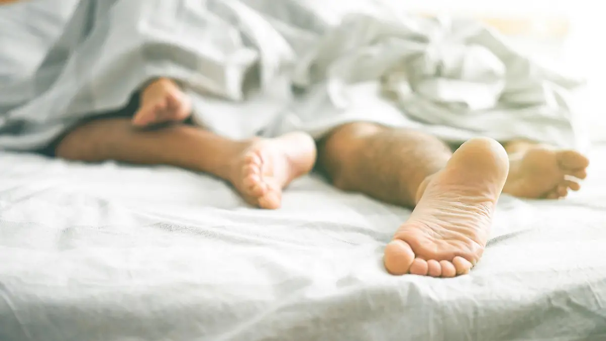 Nahaufnahme von männlichen und weiblichen Füßen auf einem Bett