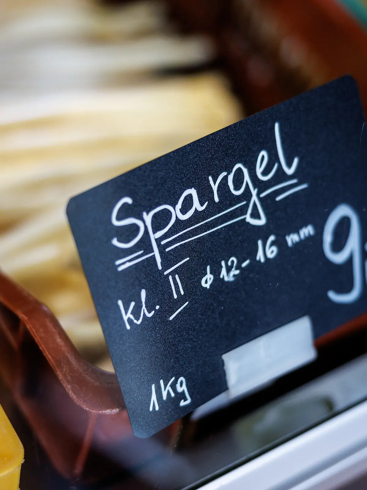 28.03.2023, Bayern, Pörnbach: Ein Schild mit der Aufschrift ·Spargel Klasse Zwei· ist im Laden eines Spargelbauers an einer Box mit Spargel zu sehen. Im Süden Bayerns hat die Ernte des Edelgemüses bereits begonnen. Foto: Matthias Balk/dpa +++ dpa-Bildfunk +++