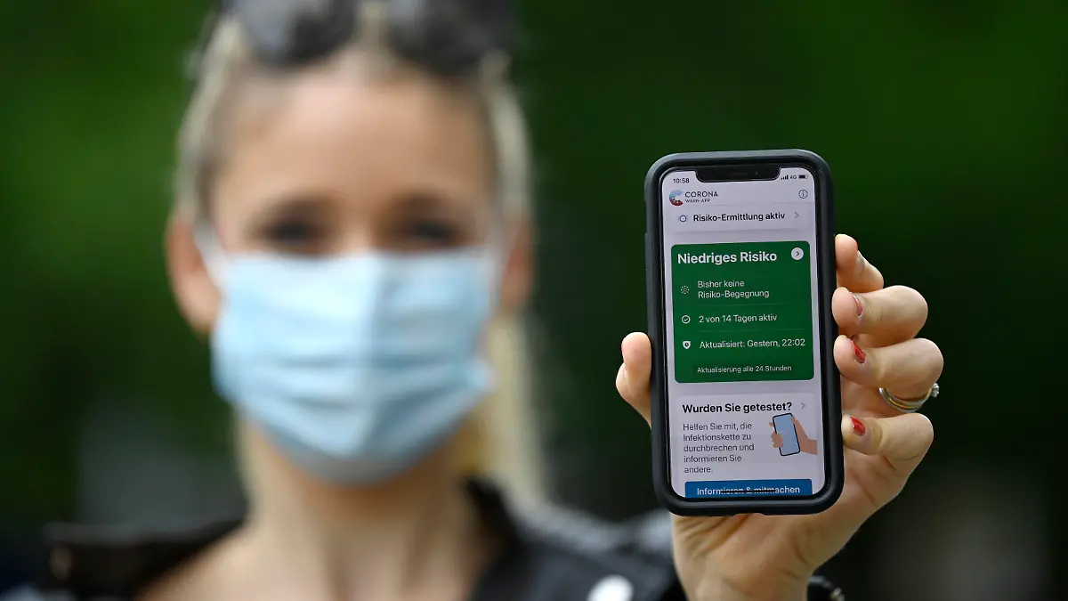 Frau mit Mundschutzmaske, zeigt Smartphone mit Corona Warn-APP im grünen Bereich, Corona-Krise, Hauptbahnhof, Stuttgart, Baden-Württemberg, Deutschland Coronavirus *** Woman with face mask, shows Smartphone with Corona Warn APP in the green zone, Corona crisis, Central Station, Stuttgart, Baden Württemberg, Germany Coronavirus
