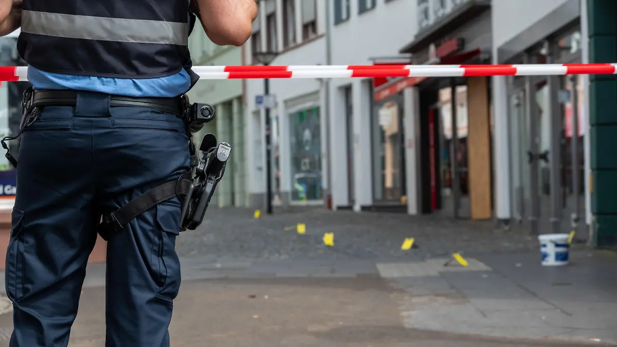 19.08.2023, Rheinland-Pfalz, Wittlich: Ein Polizist sichert die Stelle in der Strasse, in der in der Nacht auf Samstag ein junger Mann getötet worden ist. Foto: Harald Tittel/dpa +++ dpa-Bildfunk +++