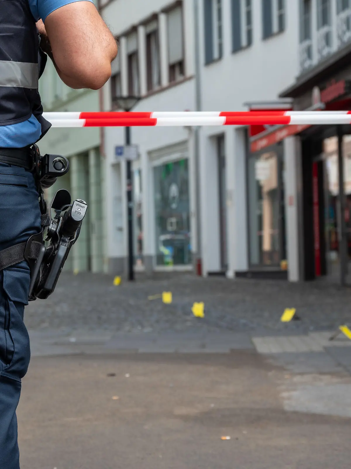 19.08.2023, Rheinland-Pfalz, Wittlich: Ein Polizist sichert die Stelle in der Strasse, in der in der Nacht auf Samstag ein junger Mann getötet worden ist. Foto: Harald Tittel/dpa +++ dpa-Bildfunk +++