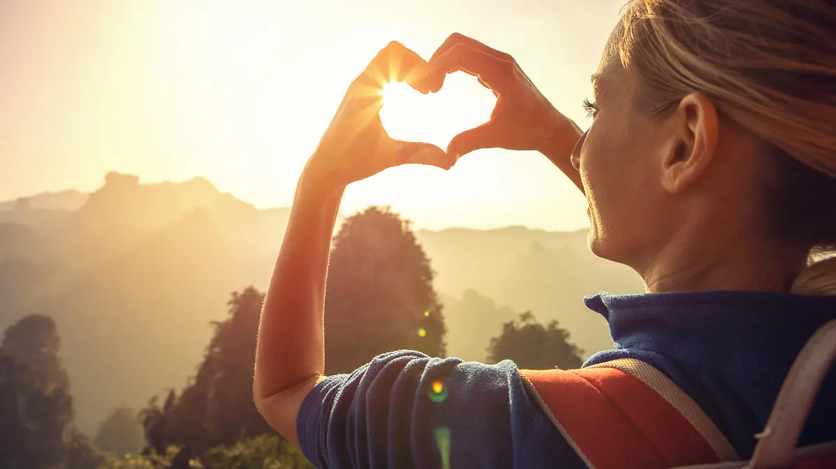 Young woman hiking in the Zhangjiajie National Forest park, makes a heart shape finger frame. Love nature wanderlust sharing concept.