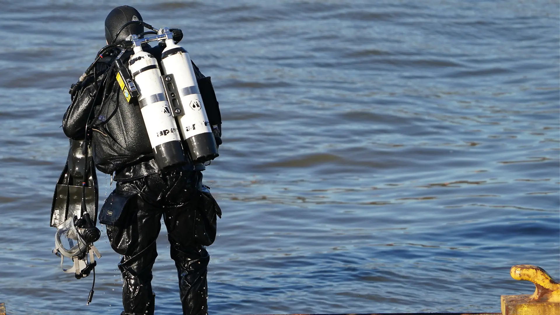 28.02.2023, Hamburg: Ein Polizeitaucher steht nach seinem Taucheinsatz in der Elbe am Fähranleger Bubendey-Ufer. Am Hamburger Fähranleger Bubendey-Ufer wird seit Dienstagvormittag in einem Großeinsatz der Polizei nach einem Jungen gesucht, der dort in die Elbe gefallen sein soll. Augenzeugen hatten versucht, das augenscheinlich zehn bis zwölf Jahre alte Kind aus dem Wasser zu holen, jedoch ohne Erfolg. Daraufhin ging der Junge nach Berichten der Helfer unter und tauchte nicht wieder auf. Die Polizei sucht nun mit Tauchern, Beamten an Land und Hubschraubern nach dem Jungen. Foto: Marcus Brandt/dpa +++ dpa-Bildfunk +++