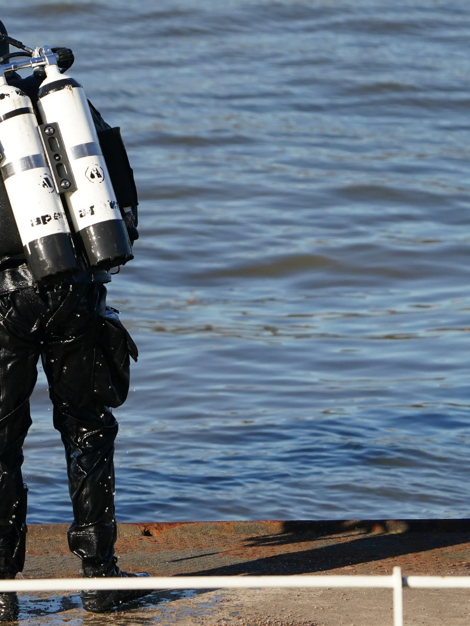 28.02.2023, Hamburg: Ein Polizeitaucher steht nach seinem Taucheinsatz in der Elbe am Fähranleger Bubendey-Ufer. Am Hamburger Fähranleger Bubendey-Ufer wird seit Dienstagvormittag in einem Großeinsatz der Polizei nach einem Jungen gesucht, der dort in die Elbe gefallen sein soll. Augenzeugen hatten versucht, das augenscheinlich zehn bis zwölf Jahre alte Kind aus dem Wasser zu holen, jedoch ohne Erfolg. Daraufhin ging der Junge nach Berichten der Helfer unter und tauchte nicht wieder auf. Die Polizei sucht nun mit Tauchern, Beamten an Land und Hubschraubern nach dem Jungen. Foto: Marcus Brandt/dpa +++ dpa-Bildfunk +++