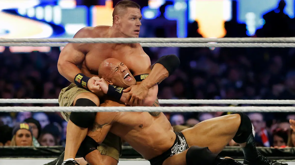 FILE -In a Sunday, April 7, 2013 file photo, wrestler John Cena, top, chokes Dwayne Douglas Johnson, known as The Rock as they wrestle during Wrestlemania, in East Rutherford, N.J. WWE bills WrestleMania as its Super Bowl, and is headed to a stadium worthy of a Super Bowl on Sunday, April 3, 2016. The WWE has lofty expectations of stuffing 100,000 fans inside AT&T Stadium in Arlington, Texas. (AP Photo/Mel Evans, File)