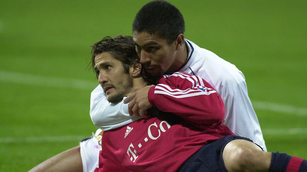 Lyons brasilianischer Stürmer Giovane Elber (r.), früher ebenfalls im Bayern-Trikot, umarmt den Münchner Bixente Lizarazu nach einem Foul. Der deutsche Fußballmeister FC Bayern München verliert am 05.11.2003 im heimischen Olympiastadion das Gruppenspiel in der europäischen Fußball-Champions League gegen den französischen Titelträger Olympique Lyon mit 1:2. Es ist die erste Niederlage im laufenden Wettbewerb. Elber erzielt den entscheidenden Treffer.
