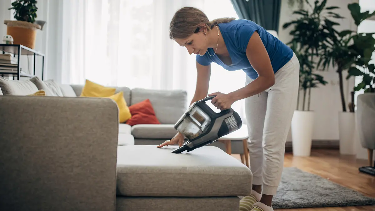 Woman vacuuming the living room with cordless vacuum cleaner