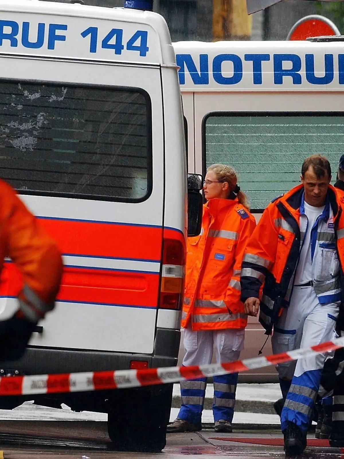 Angehörige der Zürcher Polizei und Sanitäter  warten am Montag (05.07.2004) vor dem Bürogebäude der Zürcher Kantonalbank (ZKB) am Tessinerplatz in Zürich, nachdem es in den Räumlichkeiten der ZKB am Morgen zu einer Schießerei gekommen war. Ein Finanzberater ist dort Amok gelaufen und hat zwei seiner Vorgesetzten angeschossen. Anschließend tötete er sich selbst. Das teilte die Polizei mit. Die Opfer des 56-Jährigen sind der Leiter der Finanzplanung und der Leiter der Finanzberatung. Der Täter war an seinem Arbeitsplatz am Tessinerplatz erschienen und hatte kurz darauf zu feuern begonnen. Foto: Walter Bieri dpa