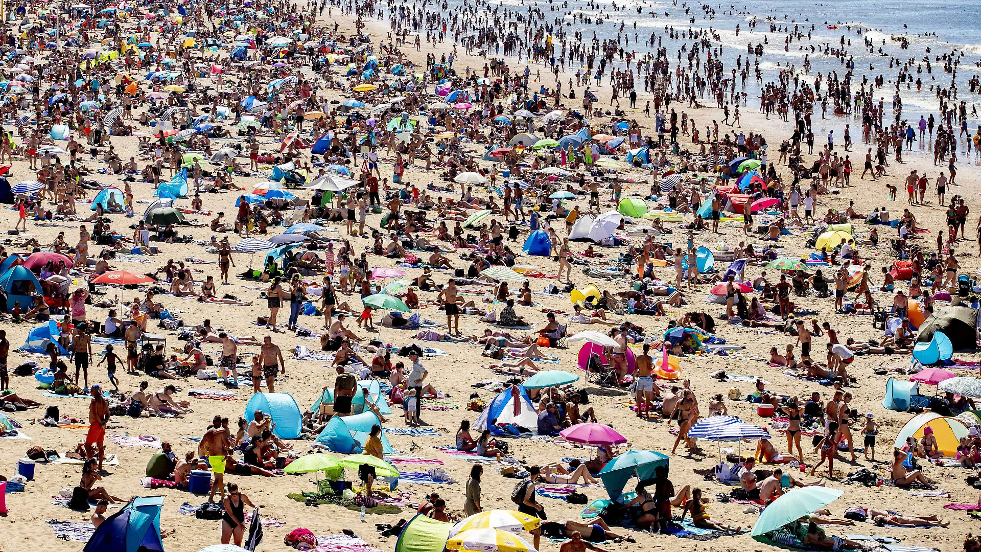 31.07.2020, Niederlande, Den Haag: Zahlreiche Menschen genießen das heiße Wetter am Strand von Scheveningen. Bei tropischen Temperaturen hat es einen Ansturm auf Strände in den Niederlanden gegeben. Die Bahngesellschaft NS warnte in einem ungewöhnlichen Aufruf Reisende, nicht in Richtung des westlich von Amsterdam gelegenen Badeorts Zandvoort zu fahren. Foto: Niels Wenstedt/ANP/dpa +++ dpa-Bildfunk +++