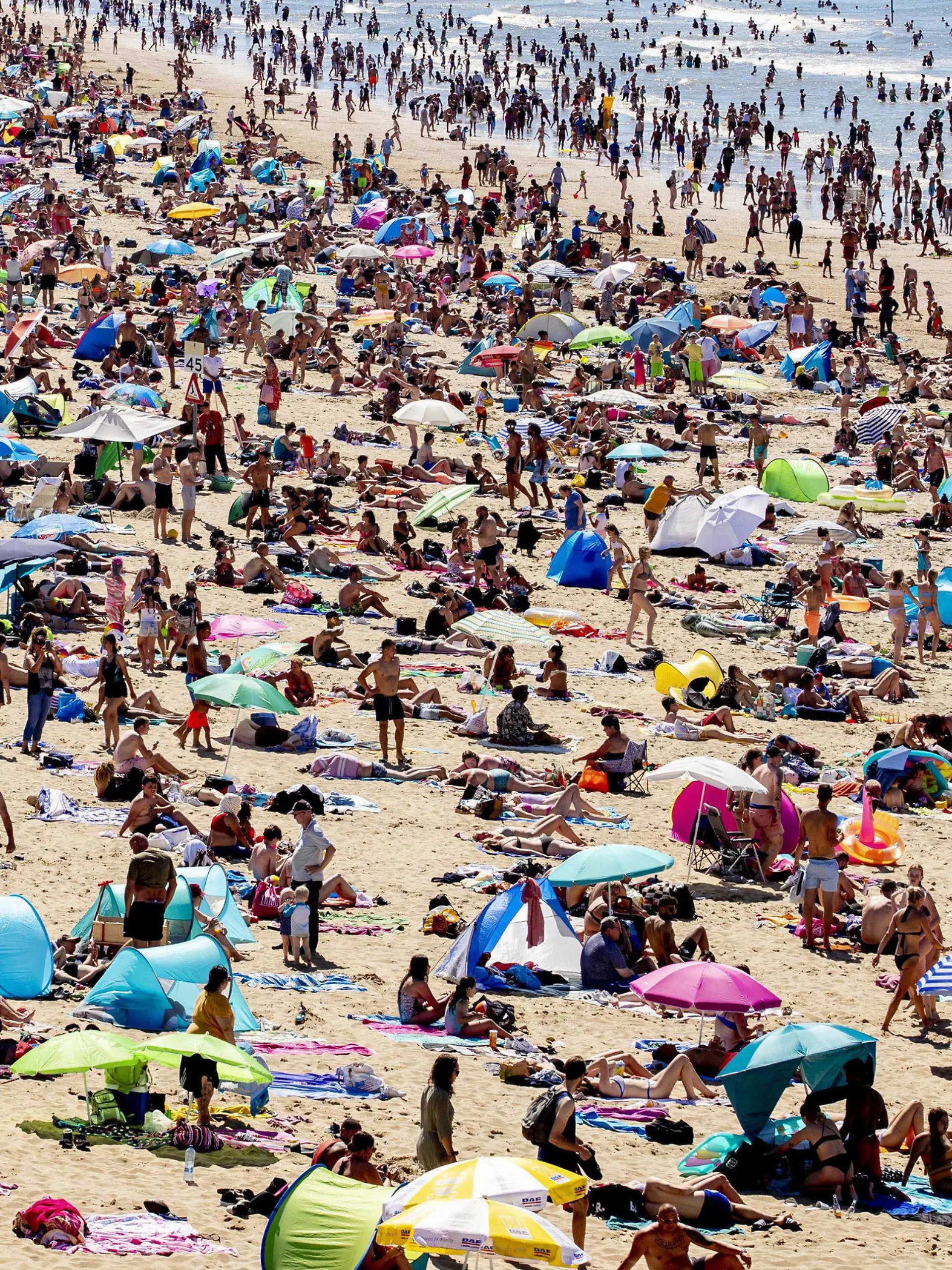 31.07.2020, Niederlande, Den Haag: Zahlreiche Menschen genießen das heiße Wetter am Strand von Scheveningen. Bei tropischen Temperaturen hat es einen Ansturm auf Strände in den Niederlanden gegeben. Die Bahngesellschaft NS warnte in einem ungewöhnlichen Aufruf Reisende, nicht in Richtung des westlich von Amsterdam gelegenen Badeorts Zandvoort zu fahren. Foto: Niels Wenstedt/ANP/dpa +++ dpa-Bildfunk +++