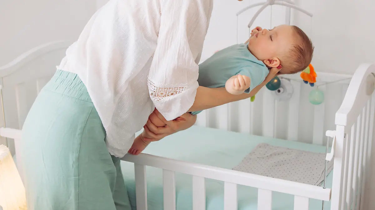 Mutter legt Baby ins Babybett