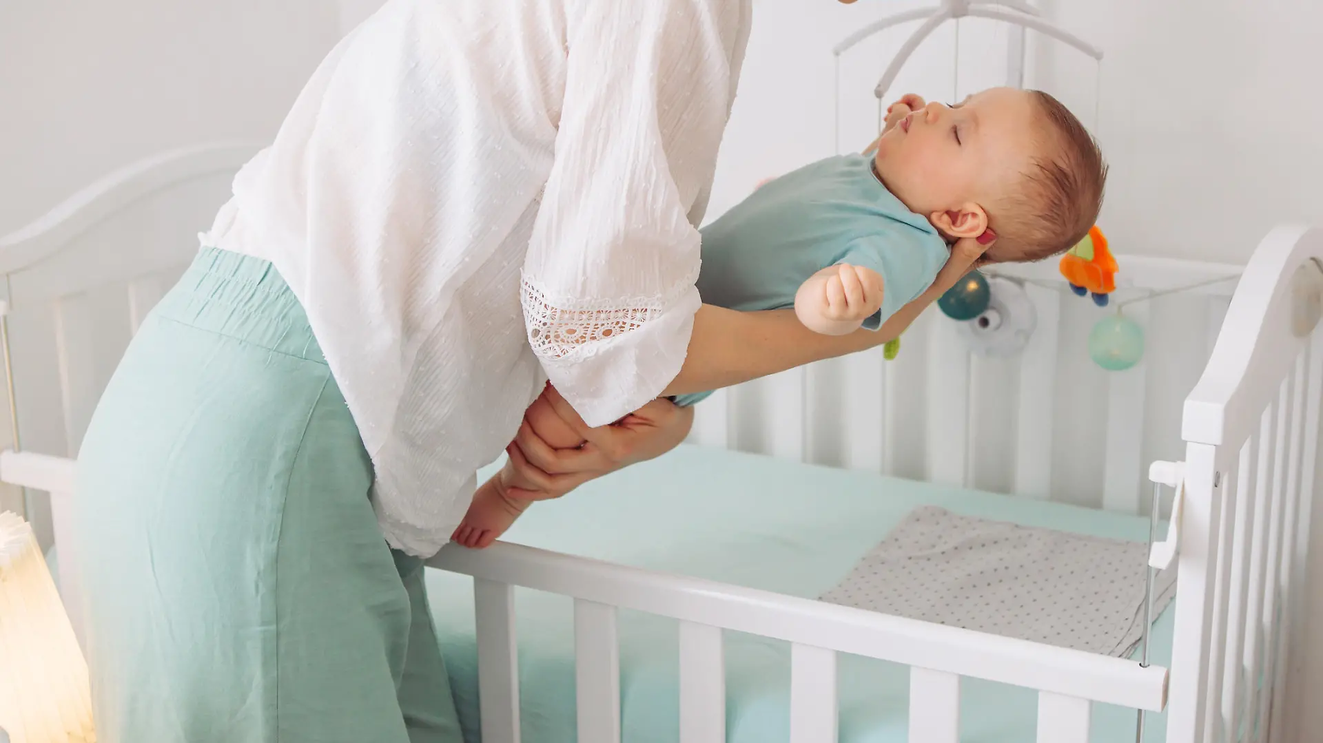 Mutter legt Baby ins Babybett