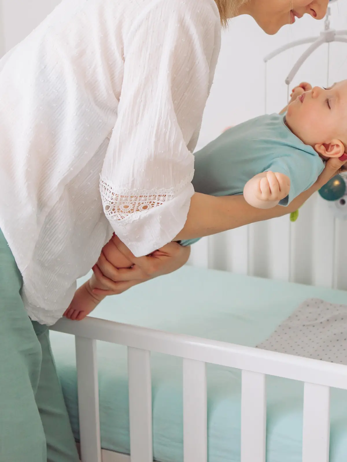 Mutter legt Baby ins Babybett