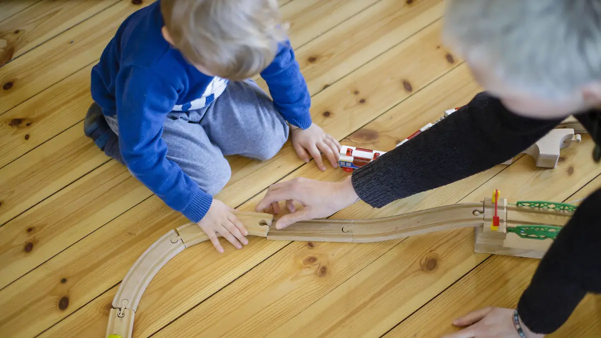Symbolfoto: Ein Kleinkind und eine Frau spielen auf dem Fussboden mit einer Holzeisenbahn. Berlin, 25.03.2020. Um die Ausbreitung des Coronavirus, COVID-19, SARS-CoV-2 zu verlangsamen, wurden in Deutschland Kindertagesstaetten geschlossen und Kinder muessen von ihren Eltern zu Hause betreut werden. Berlin Deutschland *** Symbol photo A toddler and a woman playing on the floor with a wooden train Berlin, 25 03 2020 In order to slow down the spread of the corona virus, COVID 19, SARS CoV 2, day-care centres have been closed in Germany and children have to be looked after by their parents at home Berlin Germany Copyright: xphotothek/xThomasxTrutschelx