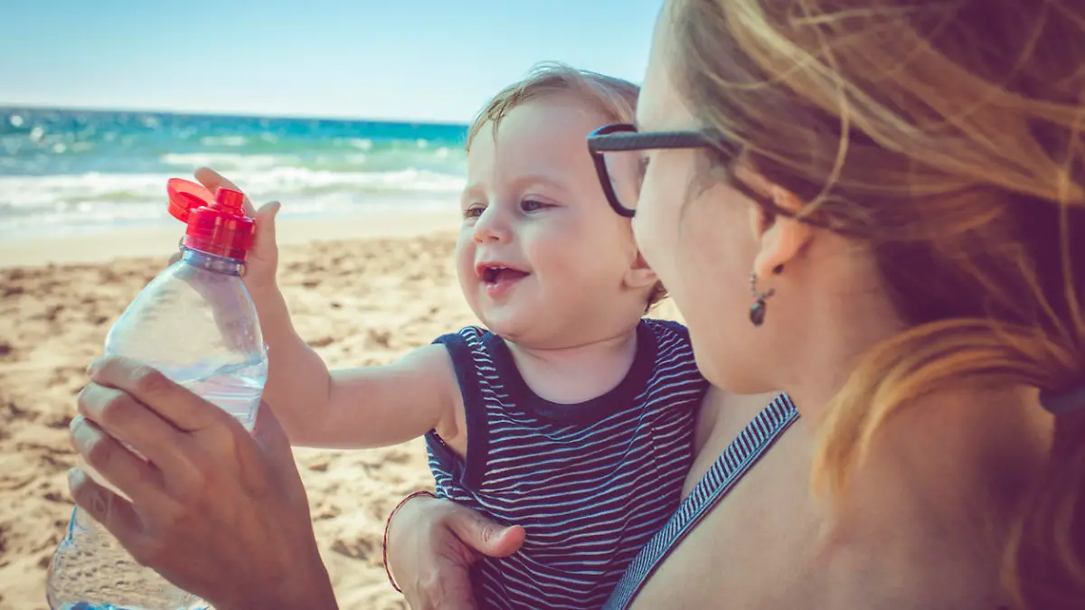 Kind und seine Mutter mit abgefülltem Wasser am Strand