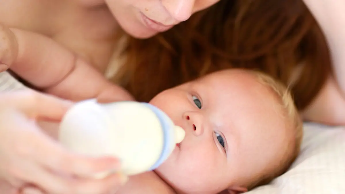 Sorgende Mutter versucht ihr Baby zu füttern mit einer Milchflasche