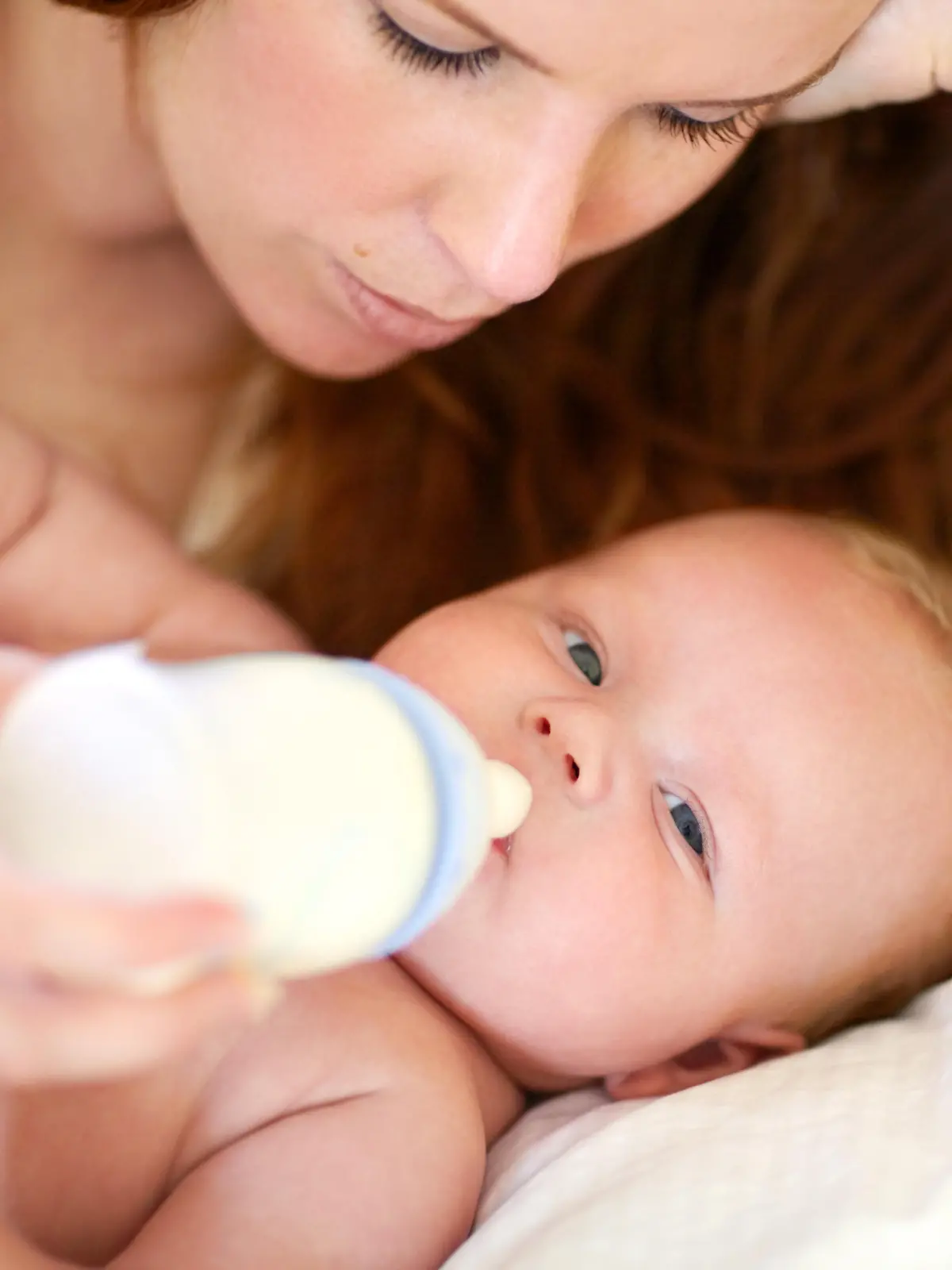 Sorgende Mutter versucht ihr Baby zu füttern mit einer Milchflasche