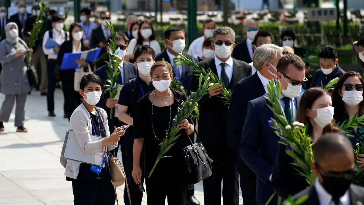 05.08.2020, Japan, Hiroshima: Diplomaten stehen vor dem Jahrestag des Atombombenabwurfs über Hiroshima Schlange, um am Kenotaph für die Atombombenopfer in der Nähe des Hiroshima Peace Memorial Museums Blumen abzulegen. Am 6. August 2020 um 8.15 Uhr (Ortszeit), also genau 75 Jahre nachdem der US-Bomber Enola Gay die erste im Krieg eingesetzte Atombombe mit dem Namen «Little Boy» über Hiroshima abgeworfen hat, legen die Menschen in Japan eine Schweigeminute ein. Foto: Eugene Hoshiko/AP/dpa +++ dpa-Bildfunk +++