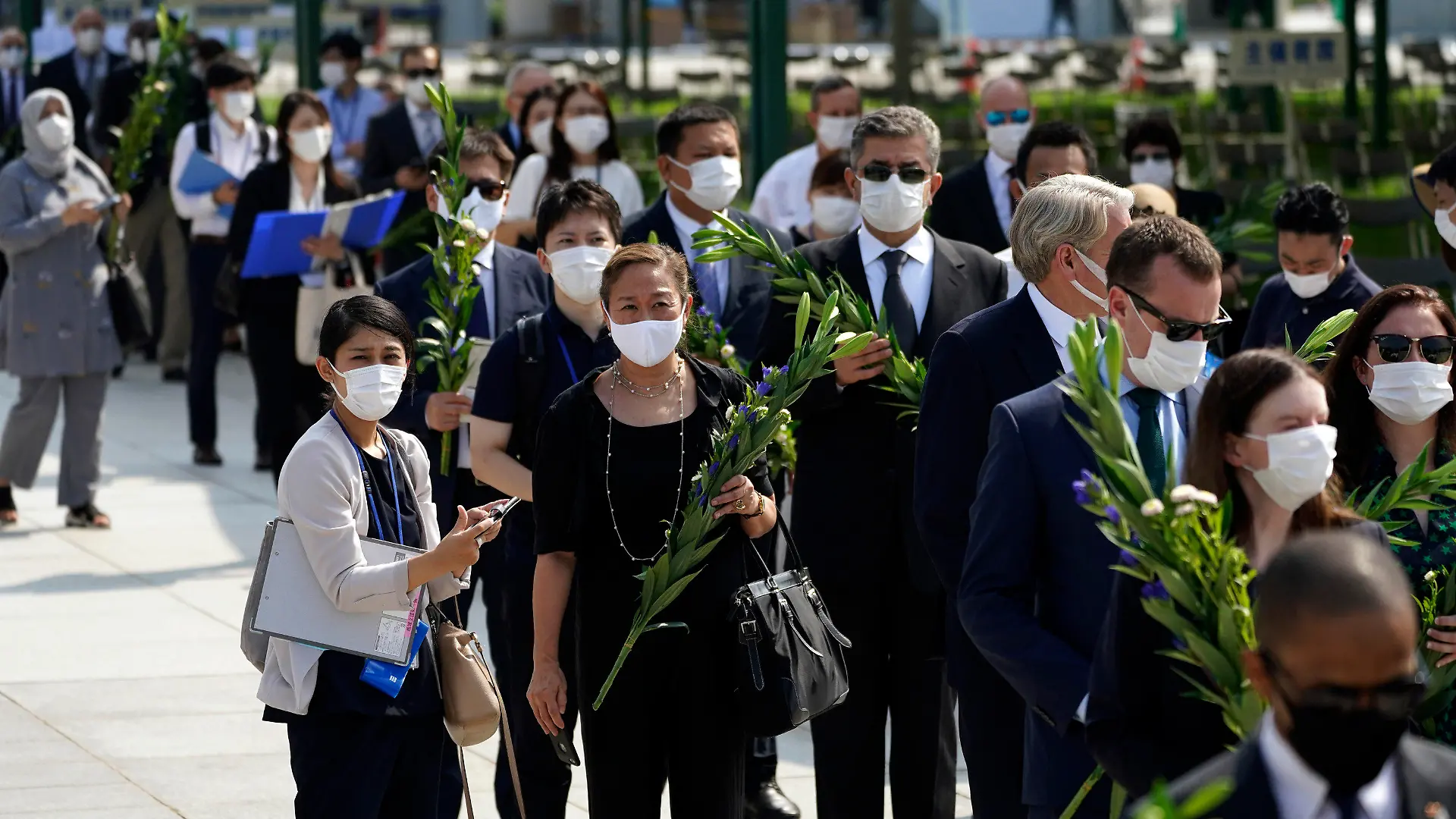05.08.2020, Japan, Hiroshima: Diplomaten stehen vor dem Jahrestag des Atombombenabwurfs über Hiroshima Schlange, um am Kenotaph für die Atombombenopfer in der Nähe des Hiroshima Peace Memorial Museums Blumen abzulegen. Am 6. August 2020 um 8.15 Uhr (Ortszeit), also genau 75 Jahre nachdem der US-Bomber Enola Gay die erste im Krieg eingesetzte Atombombe mit dem Namen «Little Boy» über Hiroshima abgeworfen hat, legen die Menschen in Japan eine Schweigeminute ein. Foto: Eugene Hoshiko/AP/dpa +++ dpa-Bildfunk +++