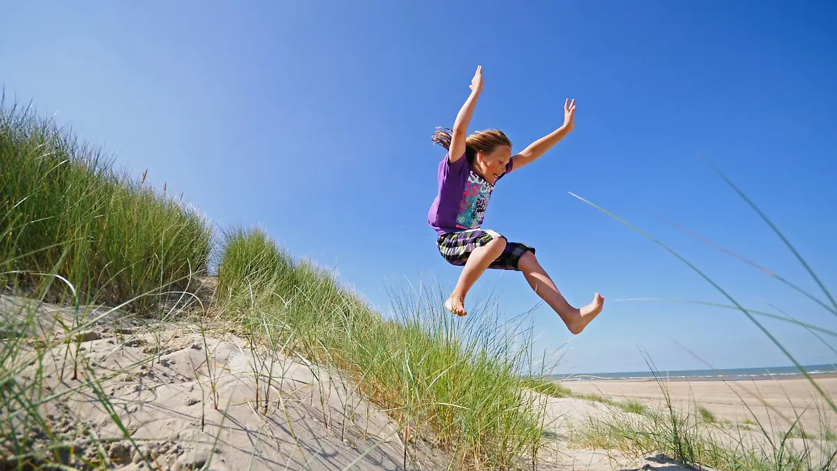 Junge springt schwungvoll aus den Duenen , Niederlande | energetic boy jumping out of the dunes, Netherlands | Verwendung weltweit