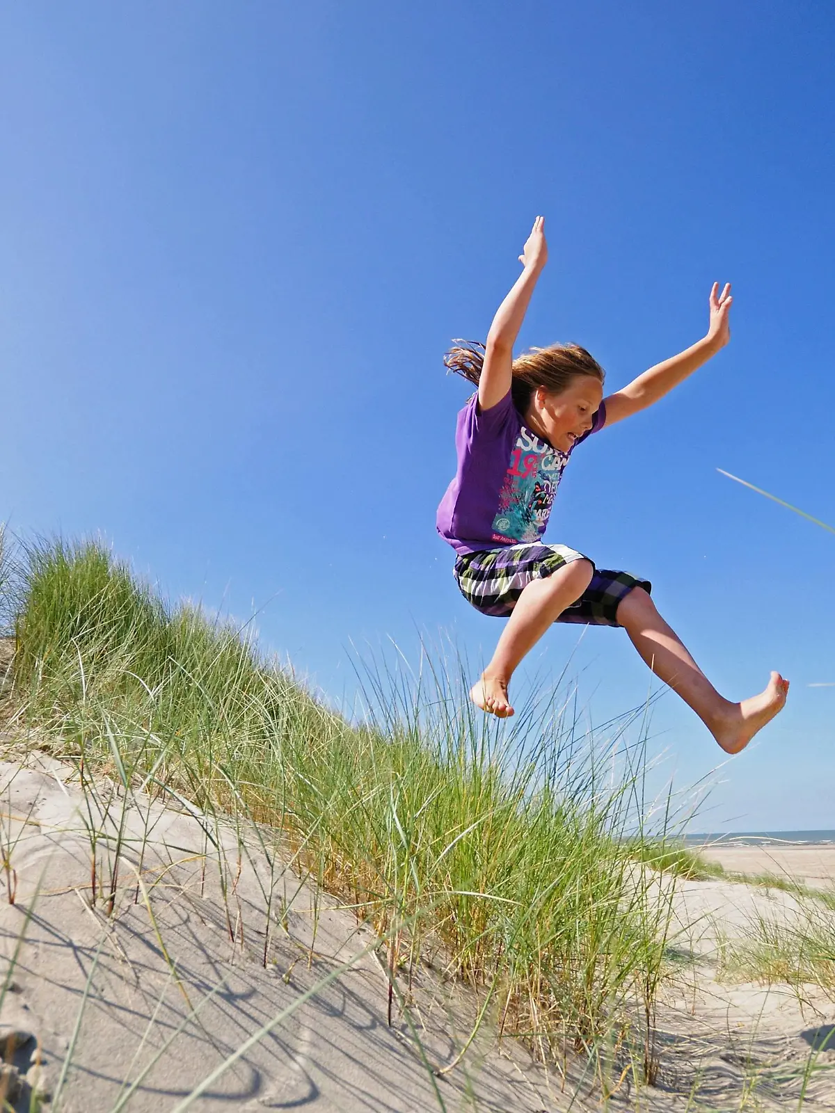 Junge springt schwungvoll aus den Duenen , Niederlande | energetic boy jumping out of the dunes, Netherlands | Verwendung weltweit