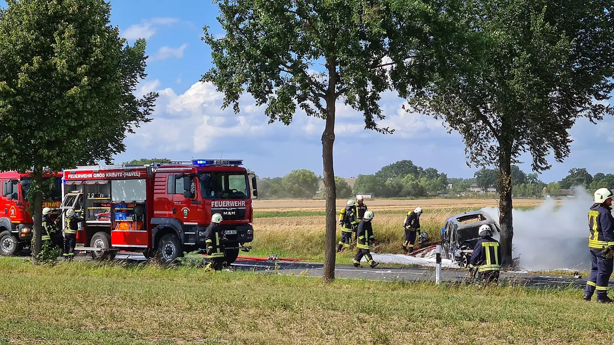 28.07.2020, Brandenburg, Groß Kreutz: Feuerwehrleute löschen das Unfallwrack eines Autos. Eine junge Fahrerin ist in Groß Kreutz bei Potsdam mit dem Auto gegen einen Baum geprallt und darin verbrannt. Es sei schwierig gewesen, die Frau in dem Elektroauto zu bergen, sagte ein Polizeisprecher. Feuerwehrleute hätten versucht, mit dem Kühlen von Akkus zu verhindern, dass die Batterien in dem Fahrzeug explodieren. (zu dpa «Fahrerin fährt gegen Baum und verbrennt im Auto») Foto: Julian Stähle/dpa-Zentralbild/dpa +++ dpa-Bildfunk +++