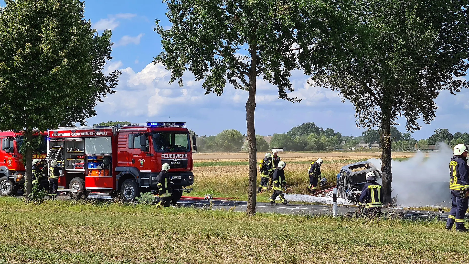 28.07.2020, Brandenburg, Groß Kreutz: Feuerwehrleute löschen das Unfallwrack eines Autos. Eine junge Fahrerin ist in Groß Kreutz bei Potsdam mit dem Auto gegen einen Baum geprallt und darin verbrannt. Es sei schwierig gewesen, die Frau in dem Elektroauto zu bergen, sagte ein Polizeisprecher. Feuerwehrleute hätten versucht, mit dem Kühlen von Akkus zu verhindern, dass die Batterien in dem Fahrzeug explodieren. (zu dpa «Fahrerin fährt gegen Baum und verbrennt im Auto») Foto: Julian Stähle/dpa-Zentralbild/dpa +++ dpa-Bildfunk +++