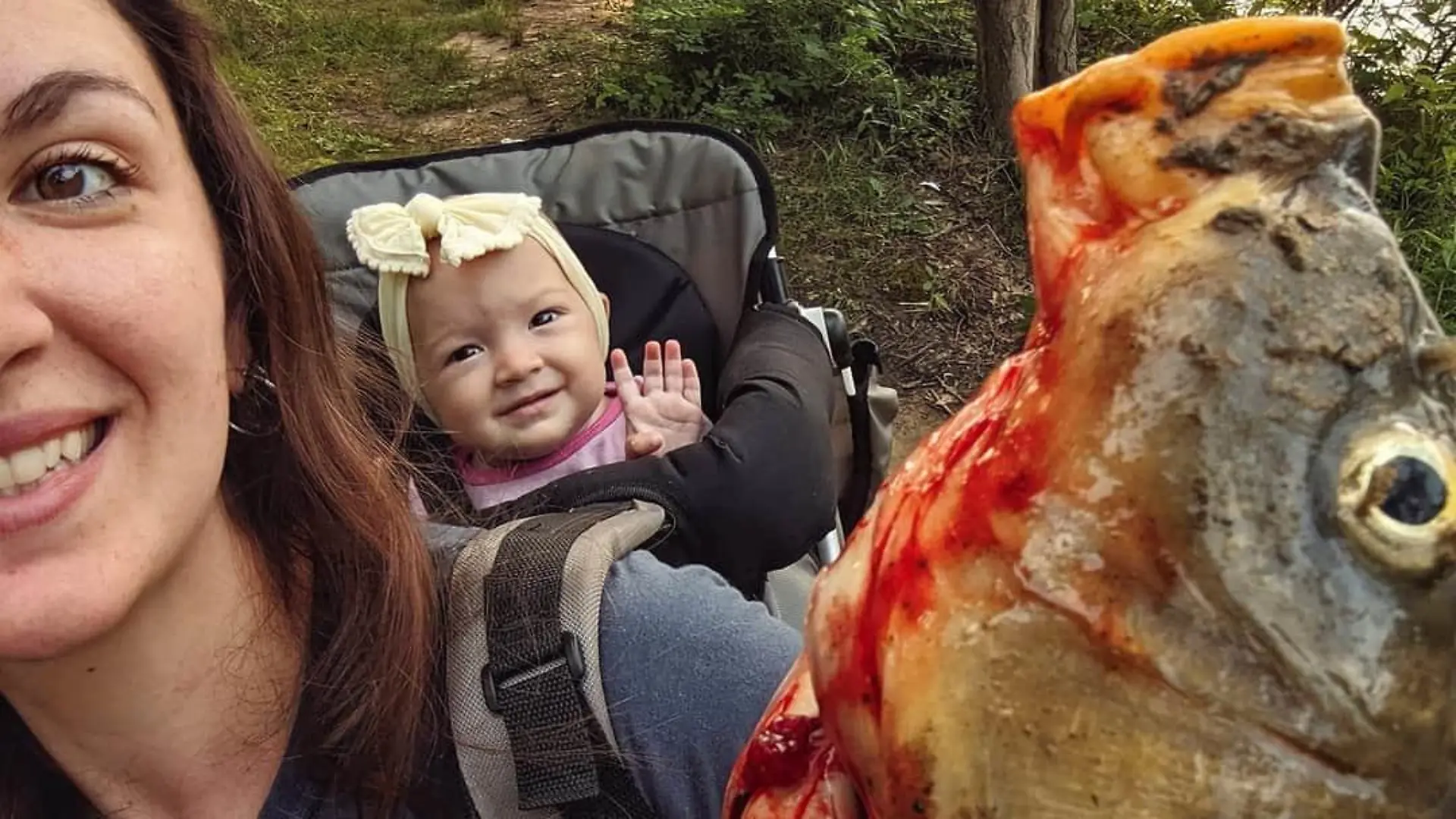 Beka Garris trägt ihre Tochter Isabella in einer Trage auf dem Rücken und einen toten Fisch in der Hand.