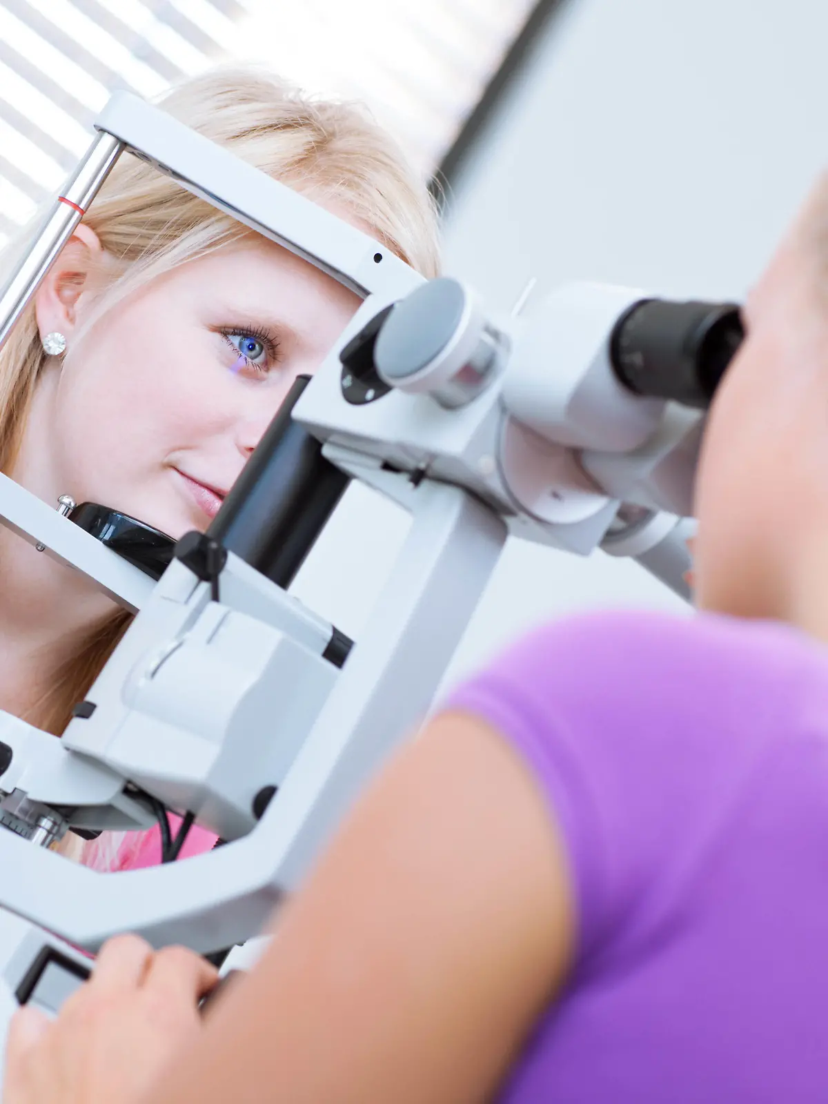 optometry concept - pretty, young female patient having her eyes examined by an eye doctor (color toned image; shallow DOF) | Verwendung weltweit, Keine Weitergabe an Wiederverkäufer.