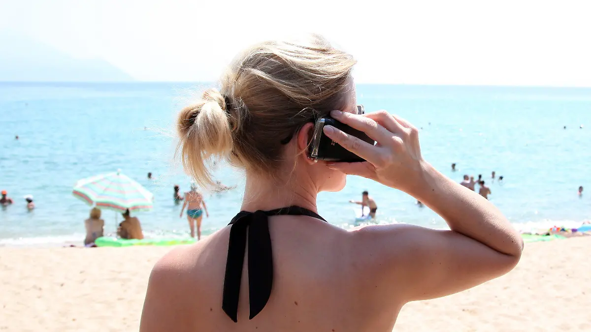 ARCHIV - Ein Frau mit Mobiltelefon steht am 11.07.2012 im griechischen Touristenort Sarti am Strand. Mehr als jeder fünfte Baden-Württemberger hat im Sommerurlaub auf Handy oder Internet verzichtet. Foto: Friso Gentsch dpa (zu lsw "Offline-Urlaub: Nur jeder Fünfte schaltet Handy oder Internet aus" vom 28.08.2012) +++(c) dpa - Bildfunk+++