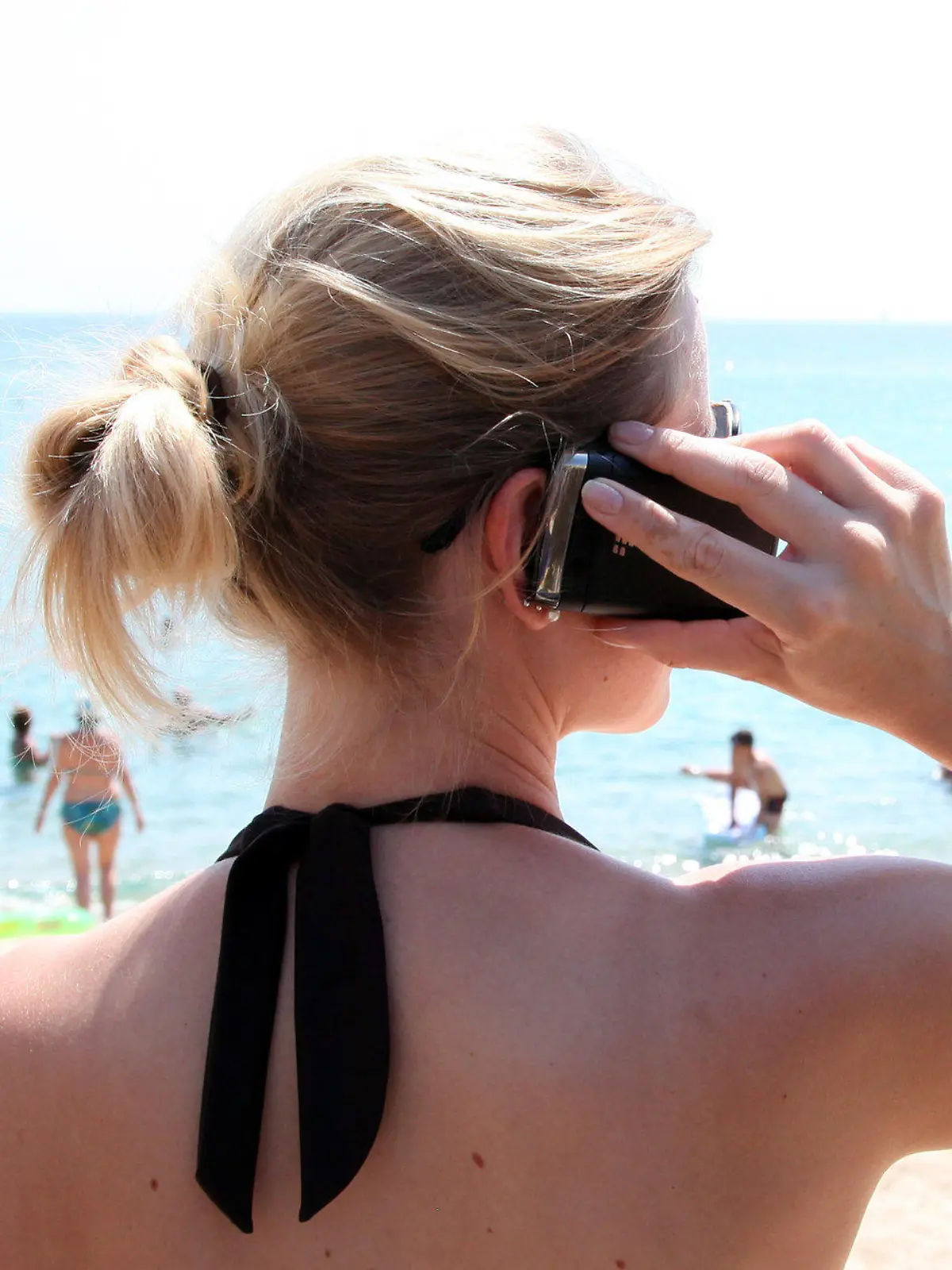 ARCHIV - Ein Frau mit Mobiltelefon steht am 11.07.2012 im griechischen Touristenort Sarti am Strand. Mehr als jeder fünfte Baden-Württemberger hat im Sommerurlaub auf Handy oder Internet verzichtet. Foto: Friso Gentsch dpa (zu lsw "Offline-Urlaub: Nur jeder Fünfte schaltet Handy oder Internet aus" vom 28.08.2012)  +++(c) dpa - Bildfunk+++