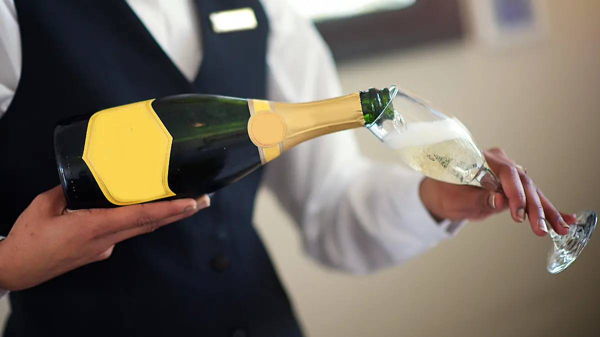 Kellner schenkt Sektglas ein