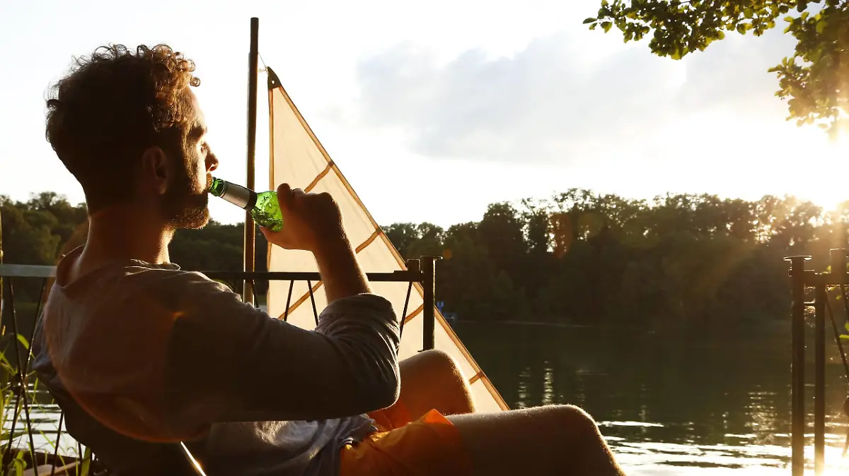 Young man with drinking a beer on a jetty next to sailing boat model released Symbolfoto PUBLICATIONxINxGERxSUIxAUTxHUNxONLY FKF02847  