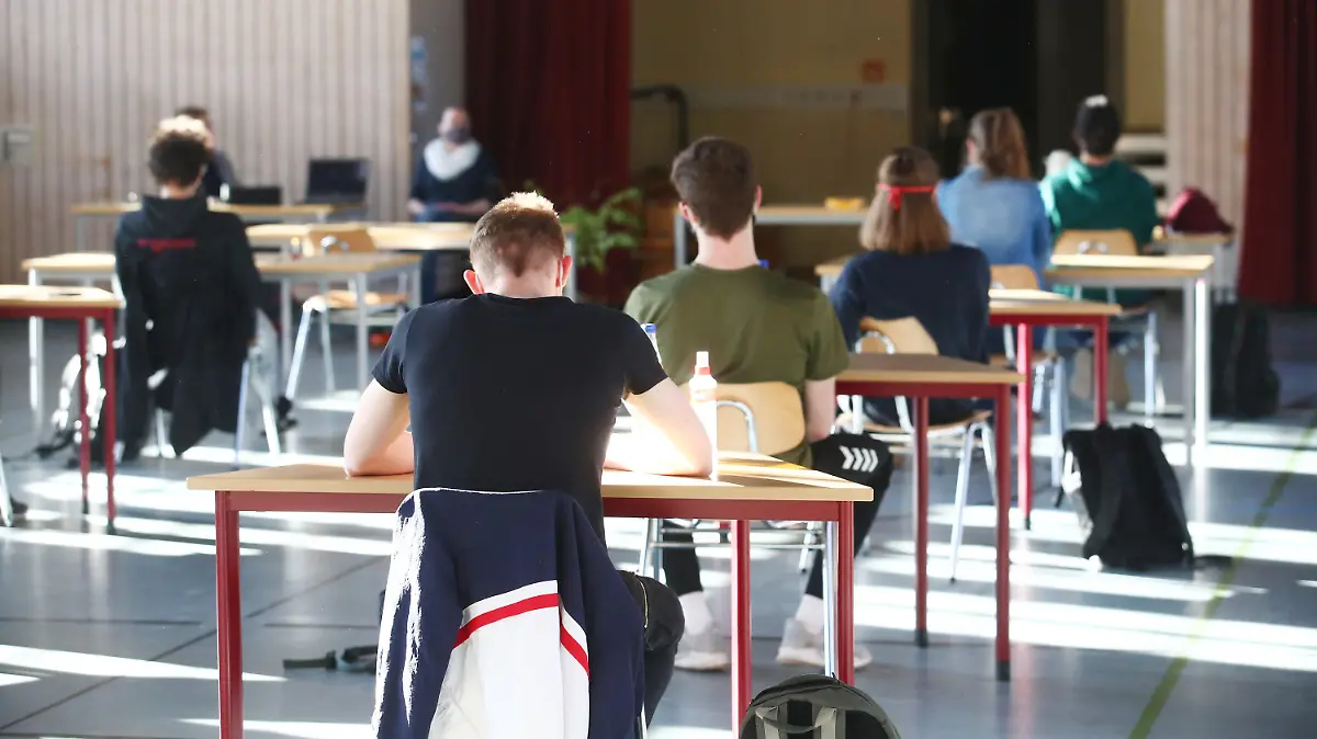 27.04.2020, Thüringen, Jena: Schüler mit Mundschutz sitzen bei der Prüfungsvorbereitung fürs Abitur in einer zum Schulraum umfunktionierten Turnhalle in der JenaPlan Schule. Nach einer mehrwöchigen Corona-Zwangspause öffnen die Schulen am 27.04.2020 wieder für die Abiturienten. Foto: Bodo Schackow/dpa-Zentralbild/dpa +++ dpa-Bildfunk +++