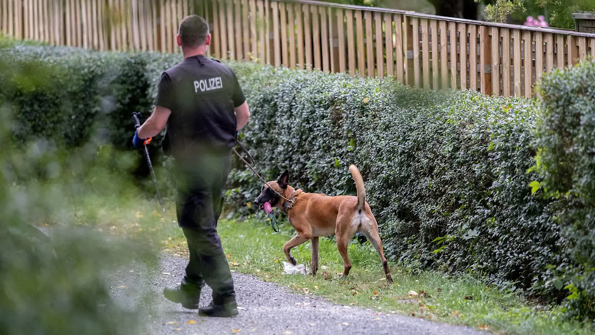 28.07.2020, Niedersachsen, Seelze: Ein Polizeibeamter mit einem Hund durchsucht eine Kleingarten-Parzelle. Im Fall der verschwundenen Maddie McCann hat die Polizei mit der Durchsuchung einer Kleingarten-Parzelle in Hannover begonnen. Foto: Peter Steffen/dpa +++ dpa-Bildfunk +++