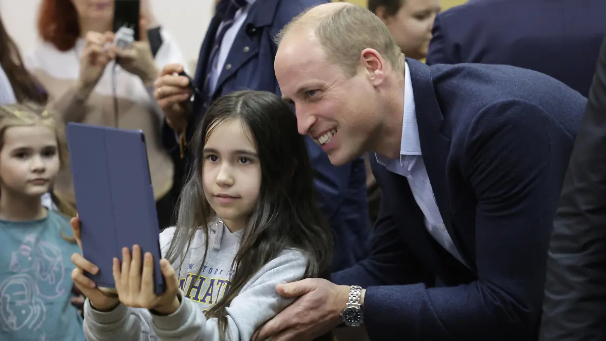 The Prince of Wales poses for photos with a young Ukrainian resident during a visit to a accommodation centre in Warsaw, Poland, which houses around 300 Ukrainian women and children who have arrived in the country more recently and are currently less integrated into Polish communities. The centre is run by the City of Warsaw and opened soon after the war in Ukraine began. Picture date: Wednesday March 22, 2023.