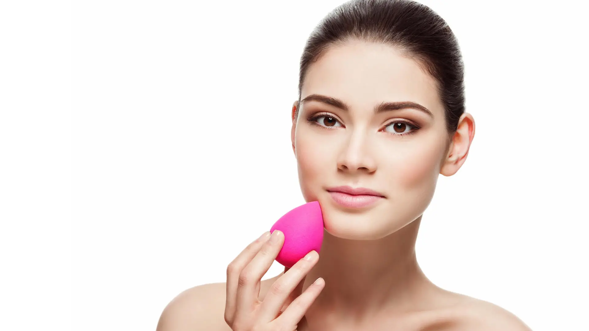 Beautiful young woman applying makeup using beauty blender sponge. Isolated over white background