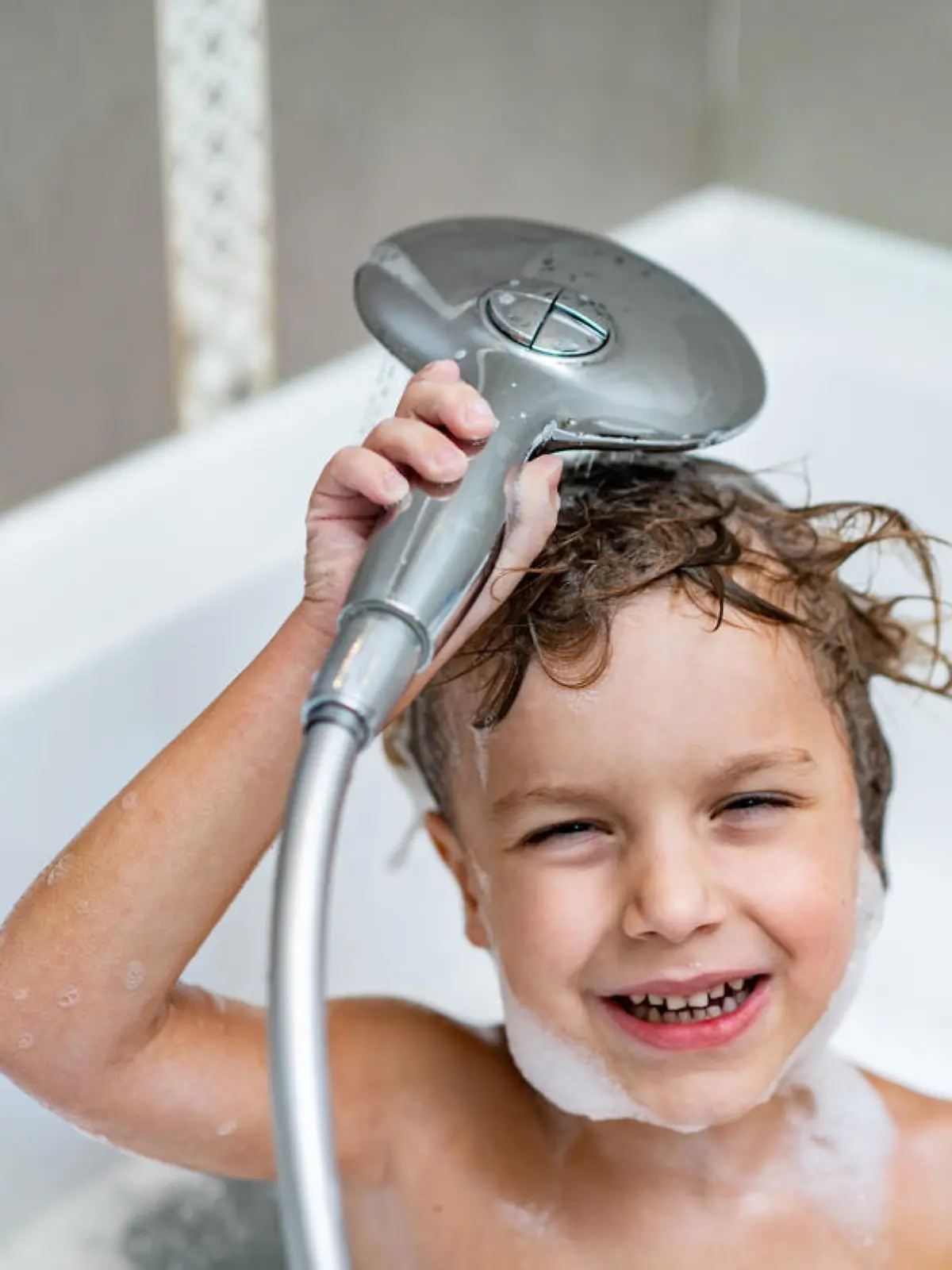 Fröhlicher Junge duscht in der Badewanne