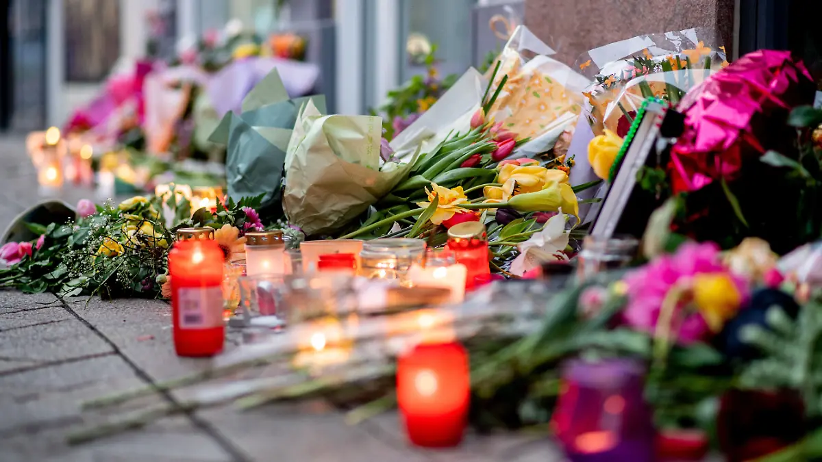 22.04.2025, Niedersachsen, Oldenburg: Zahlreiche Blumen und Kerzen stehen in der Innenstadt an einer Hauswand in der Achternstraße, in der am frühen Sonntagmorgen ein Mensch von Schüssen aus einer Polizeiwaffe tödlich verletzt wurde. Der 21-Jährige hatte zuvor vor einer Diskothek Reizgas versprüht und mehrere Menschen leicht verletzt. Foto: Hauke-Christian Dittrich/dpa +++ dpa-Bildfunk +++
