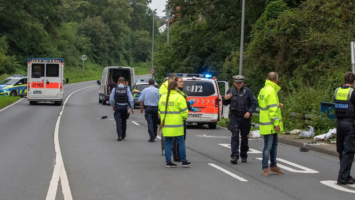 Polizisten stehen auf einer Straße in dem Ort bei Aachen, wo zuvor ein Kleintransporter eine Mutter und ihr Kind an einer Bushaltestelle erfasst und tödlich verletzt hatte.