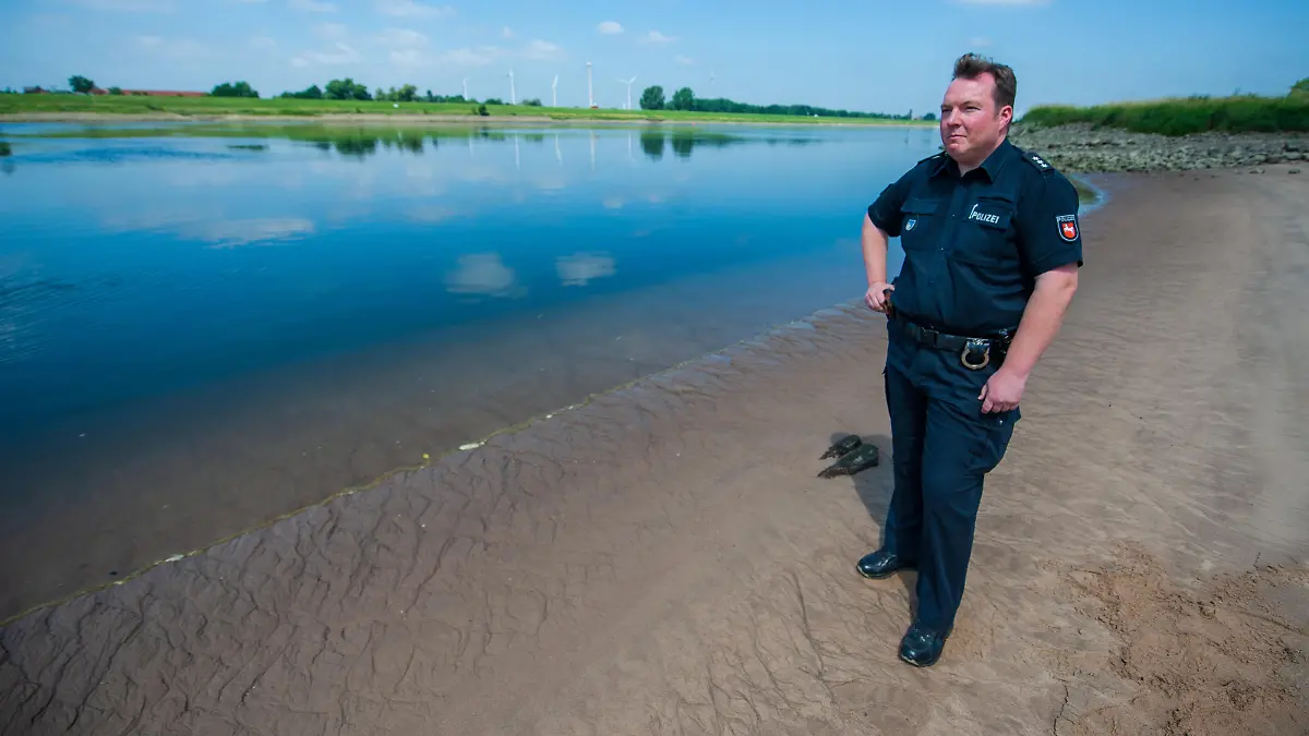 26.06.2018, Niedersachsen, Drage: Jan Krüger, Polizeisprecher, steht am Elbstrand bei Drage. Die Familie aus dem kleinen Ort an der Elbe verschwindet spurlos. Wenig später wird der Vater tot aus dem Fluss gezogen, seine Ehefrau und die zwölfjährige Tochter bleiben vermisst. Auch für erfahrene Polizisten bleibt der Fall etwas Besonderes, auch drei Jahre später. (zu dpa "Drage - zwei Menschen verschwinden spurlos" vom 08.07.2018) Foto: Philipp Schulze/dpa | Verwendung weltweit