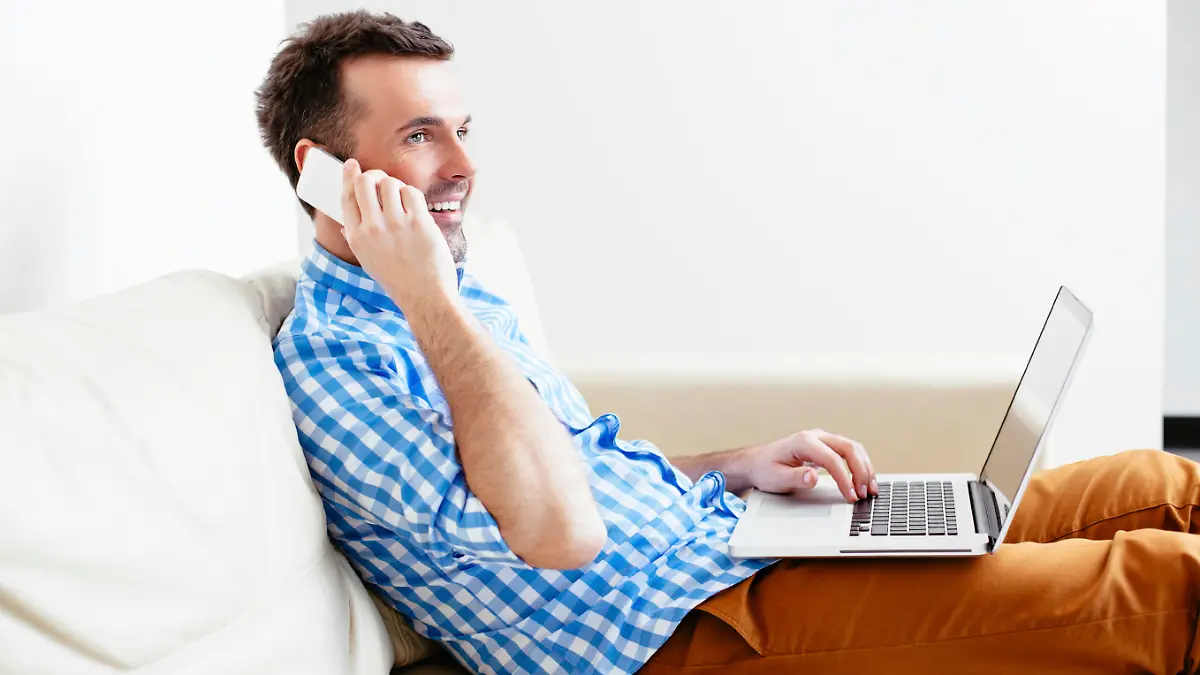Young man relaxing on his sofa and making a call on his mobile