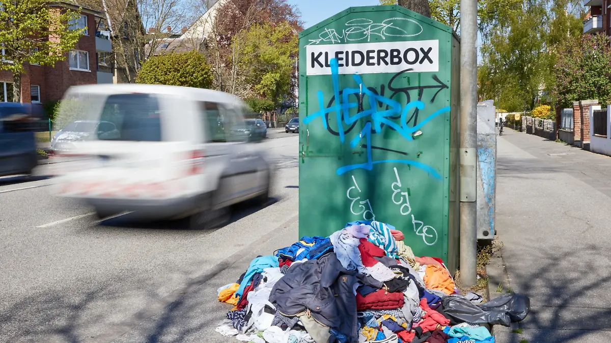 ARCHIV - 23.04.2020, Schleswig-Holstein, Lübeck: Ein Kleiderberg liegt vor einem Altkleidercontainer mit der Aufschrift «Kleiderbox» am Straßenrand. Der Kleiderschrank frisch sortiert, die ungeliebten Stücke in Säcken verstaut und in den Fächern wieder Platz für Neues: Weil viele Menschen in Deutschland die Corona-Zwangspause für ausgiebiges Ausmisten nutzten, gelangen Textil-Recycler an ihre Grenzen. (Wischeffekt durch Langzeitbelichtung) Foto: Georg Wendt/dpa +++ dpa-Bildfunk +++